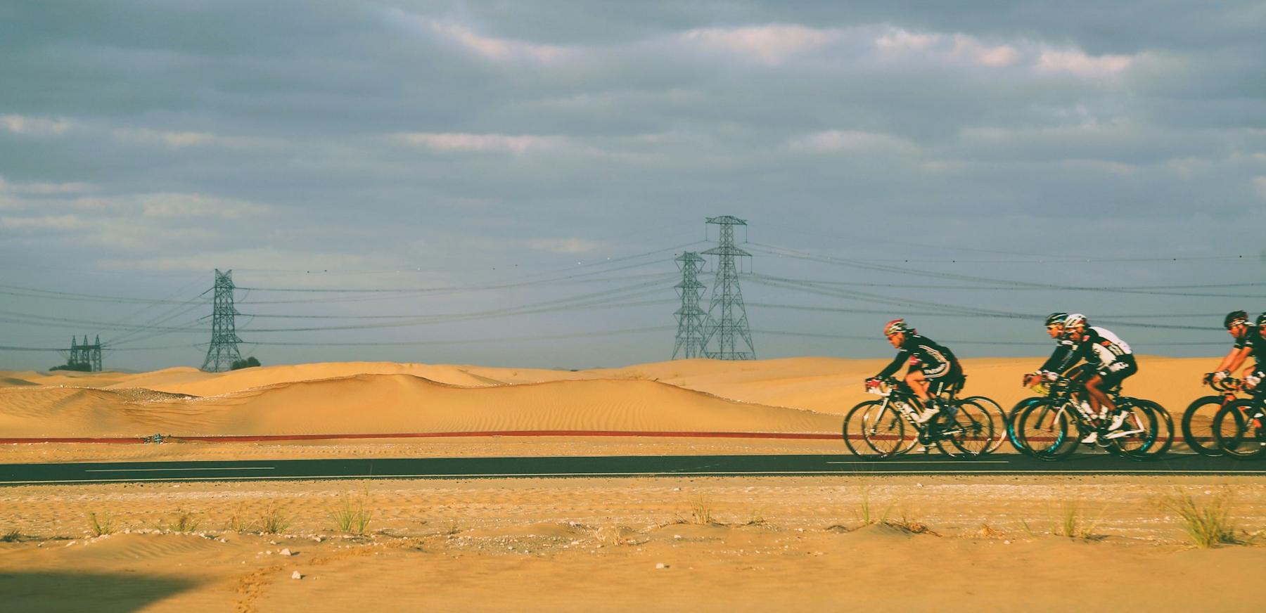 Cyclistes sur route au milieu des dunes du désert